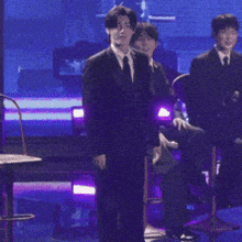 a group of men in suits are sitting on a stage