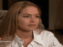 a woman in a white shirt is sitting in front of a sign that says novela