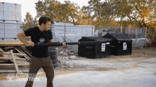 a man in a black shirt is standing in front of a dumpster that says jacksmith industries