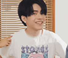 a young man wearing a rolling stones t-shirt is smiling