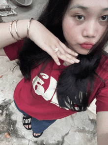 a woman wearing a red shirt with a panda on it is taking a selfie
