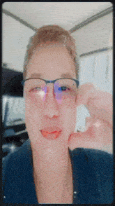 a close up of a person wearing glasses making a heart shape with their hand