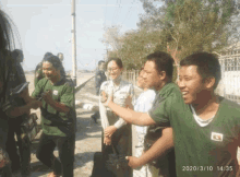 a group of people are standing in front of a fence with the date 2020/3/10 14:25