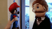 a person is holding a mario puppet next to another puppet