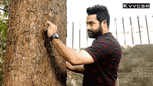 a man standing next to a tree with a kvvcsr logo on the bottom