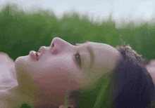 a close up of a woman 's face laying in the grass