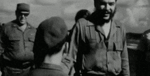 a black and white photo of a man in a military uniform talking to a man in a military uniform .