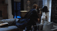 a man and a woman are fighting in a living room at night