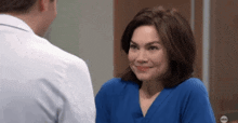 a woman in a blue scrub top is smiling at a doctor .