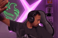 a man wearing headphones is sitting in a chair with his arms outstretched .