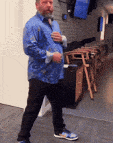 a man in a blue shirt and black pants is standing in a room with a clock on the wall