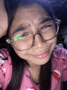 a girl wearing glasses and a pink pajama top