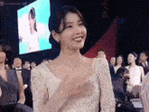 a woman in a white dress is smiling and clapping her hands