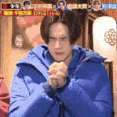 a man in a blue jacket is praying in front of a sign that says ' 少年 '