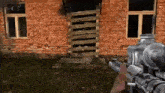 a person is holding a gun in front of a brick building with stairs .