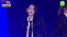 a woman in a suit and tie is dancing on a stage in front of a microphone .