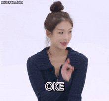 a woman in a blue sweater with the word oke written on her chest