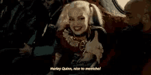 a woman in a harley quinn costume is giving a thumbs up while sitting in a car .