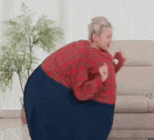 a woman in a red sweater is dancing in a living room .