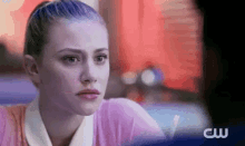 a woman with blue hair is sitting at a table in a diner looking at the camera .