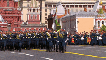 a group of soldiers march down a street in front of a building that says ' 00 ' on it