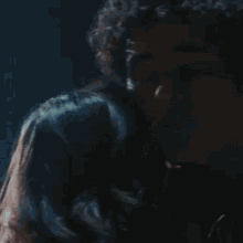 a close up of a man 's face with curly hair in a dark room