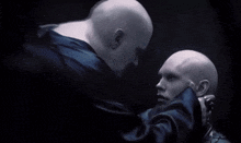 a couple of bald men are standing next to each other in a dark room .