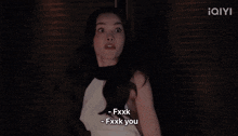 a woman in a white and black top is standing in a dark room with the word iqiyi on the bottom