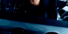 a man is sitting in the back seat of a car looking out the window .