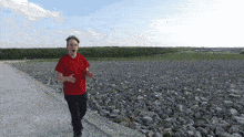a man in a red shirt is running on a rocky hillside