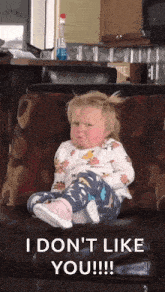 a little girl is sitting on a couch with her legs crossed and says i don 't like you .