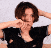 a woman with short hair is holding her hair in a ponytail while wearing a black shirt