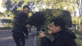 a man in a black jacket is standing next to another man