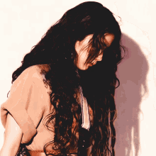 a woman with long curly hair looks down at something