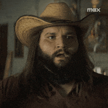 a man with long hair and a beard wearing a cowboy hat with the word max on the bottom right
