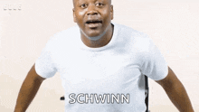 a man in a white t-shirt is riding a bicycle .