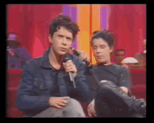 a man in a denim jacket is holding a microphone