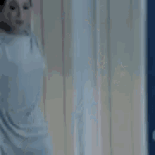 a woman in a white dress is smiling and dancing in a room .