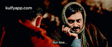 a man with a scarf around his head talks on a cell phone with another man .