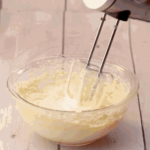 a person is mixing a brown liquid in a glass bowl
