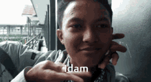a young man is making a funny face and the word idam is on the bottom