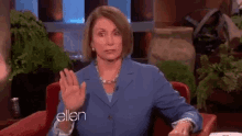 a woman in a blue suit is sitting in a red chair with ellen written on the front of her jacket
