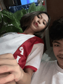 a man and a woman are posing for a picture with the woman wearing a red and white shirt with the number 9 on it