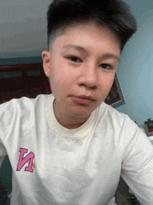 a young man taking a selfie with a white shirt with the letter v on it