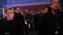 a man in a black jacket is standing next to a woman in a red light with #svu on the bottom