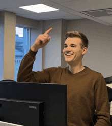 a man is pointing at something in front of a thinkvision computer monitor