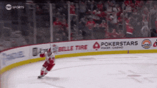 a hockey player is skating on the ice in front of a banner that says pokerstars
