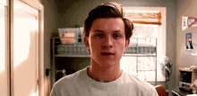 a young man in a white t-shirt is standing in a room .
