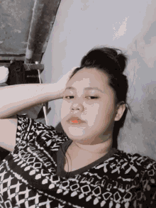 a woman laying down with her hand on her head wearing a black and white shirt