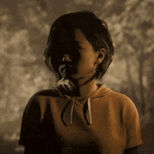 a woman wearing a yellow hoodie is standing in the dark